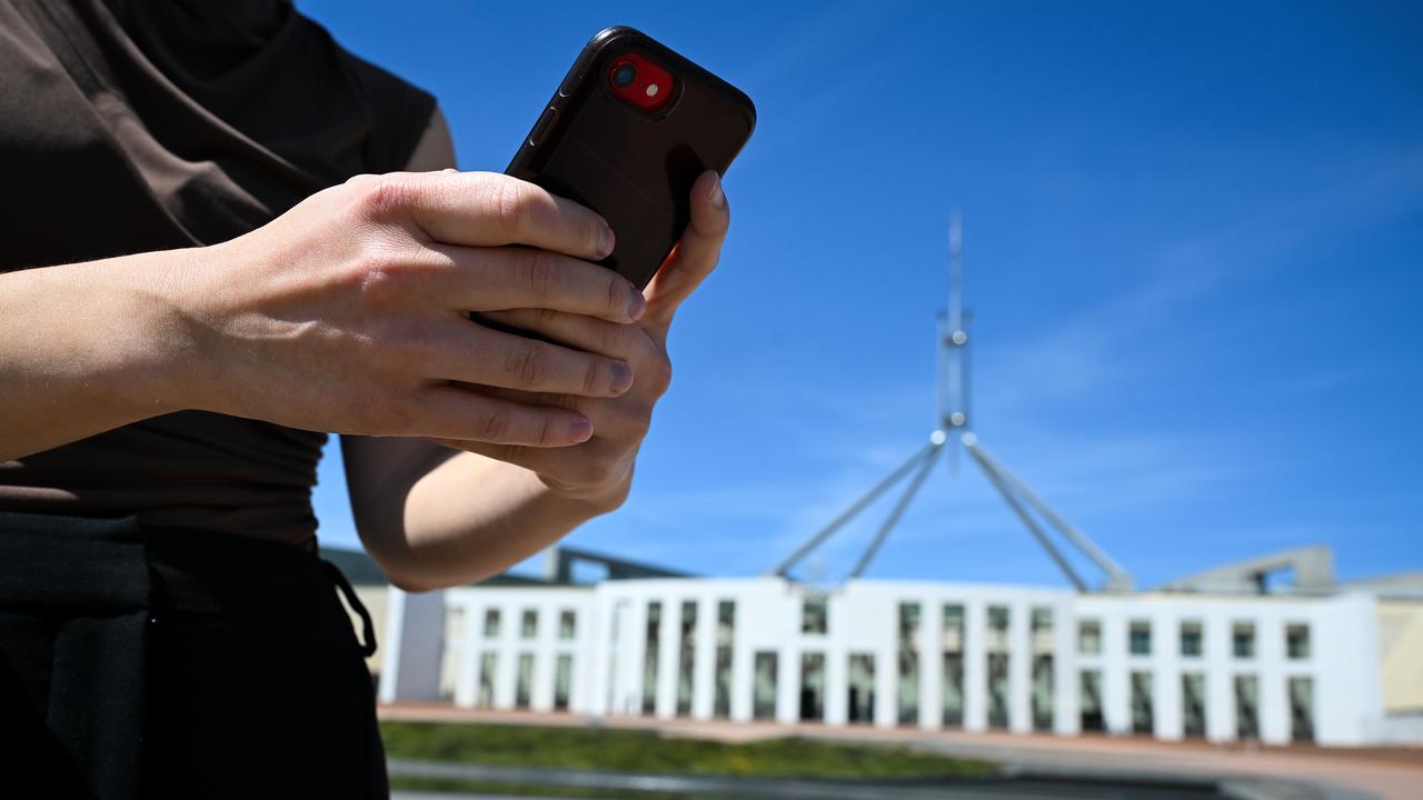 Woman checks her phone outside Parliament House in Canberra