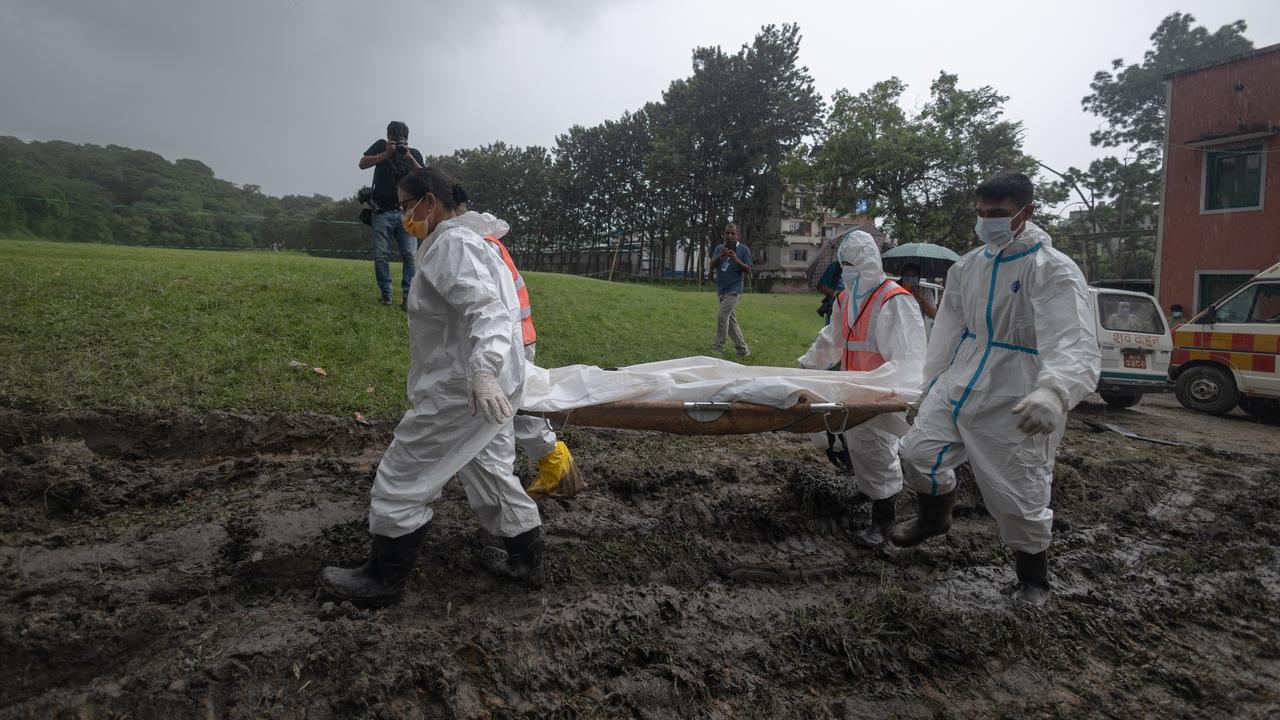 Officers carry the bodies of unidentified victims to a mass grave