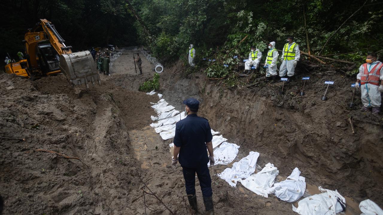 An excavator moves soil over the bodies of unidentified victims