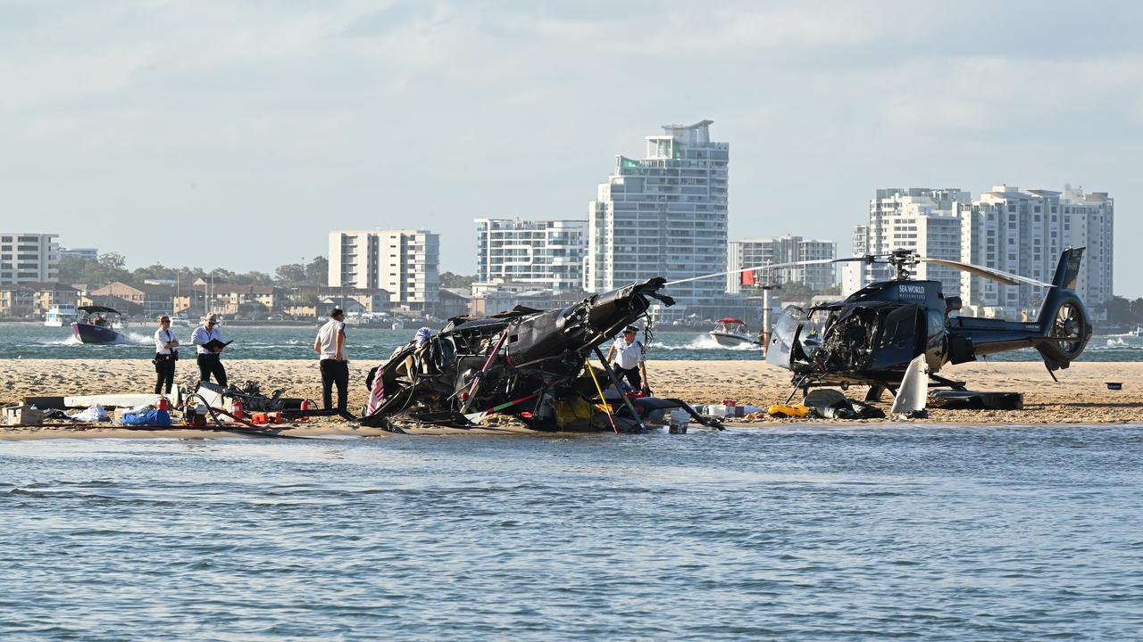 two helicopters , one upside down, on a beach