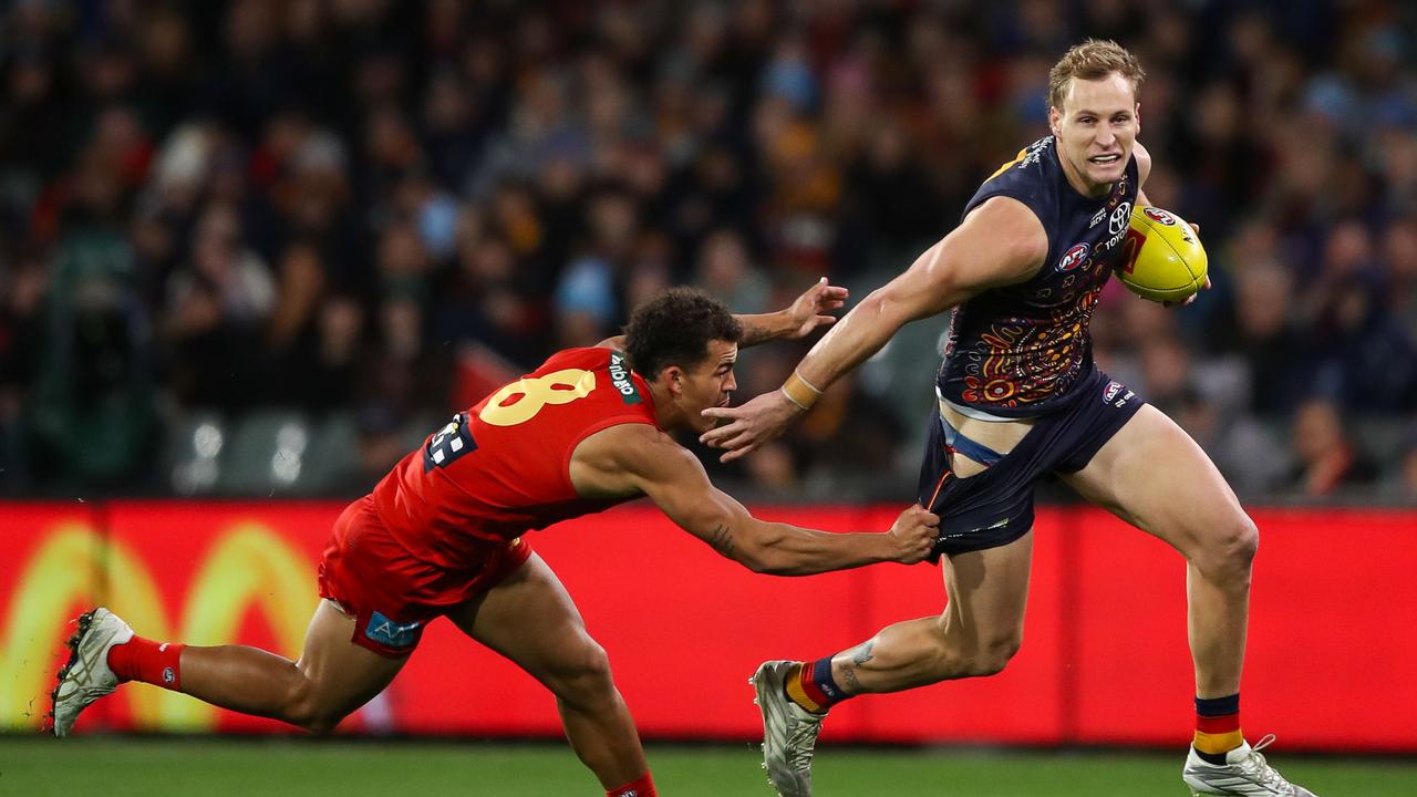 Jordan Dawson of the Crows is tackled by Leonardo Lombard
