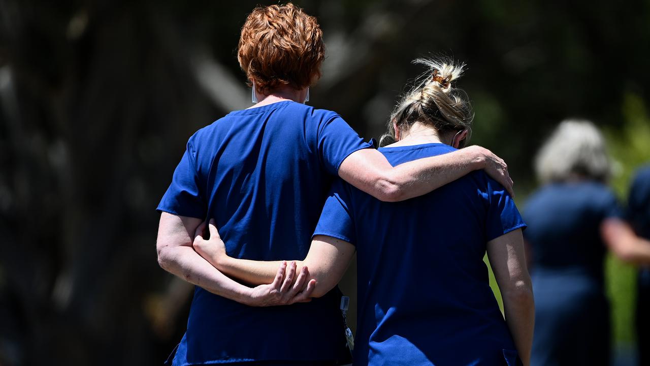healthcare workers embrace at scene of tribute