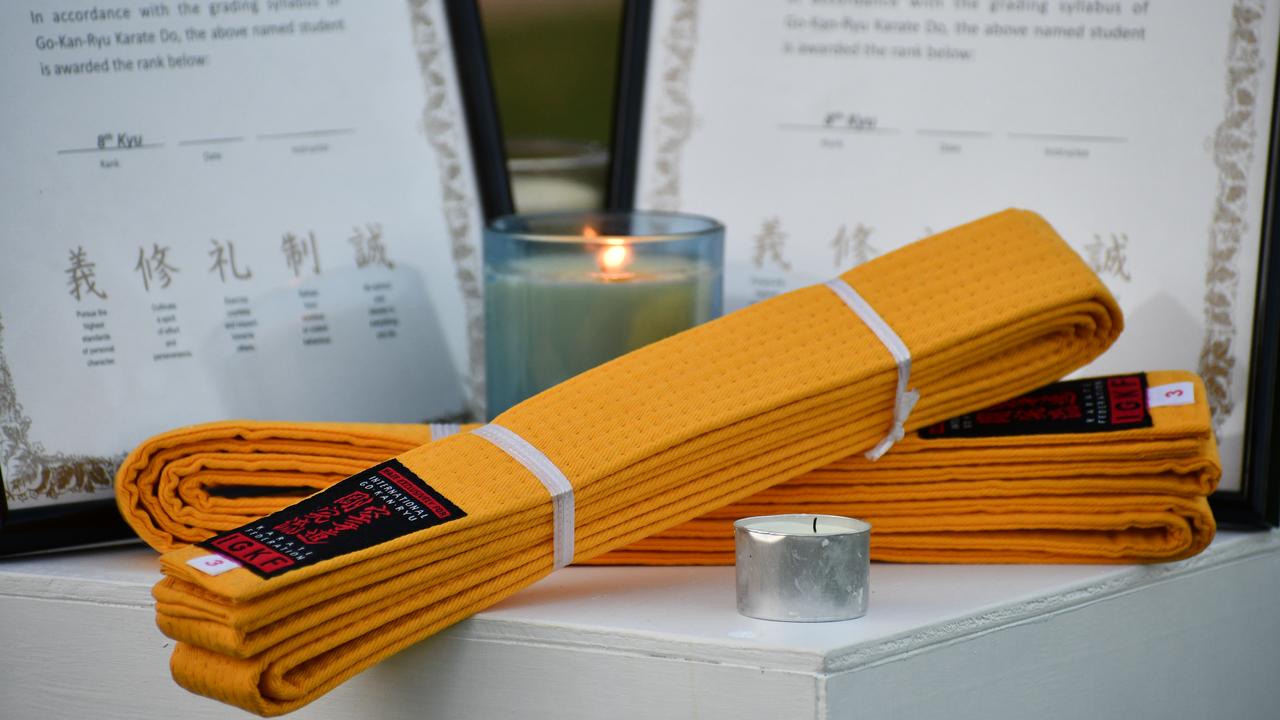 Karate belts and certificates near candles