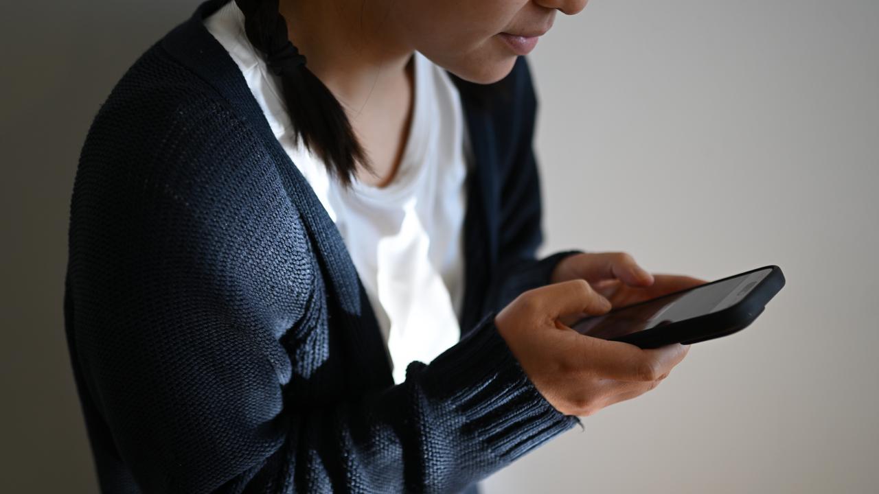 A photo illustration of a young woman on her mobile phone.